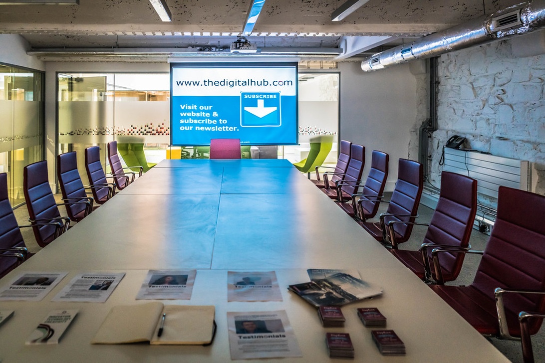 Samtida konferensrum med ovalt bord, färgstarka stolar och industriella designelement.