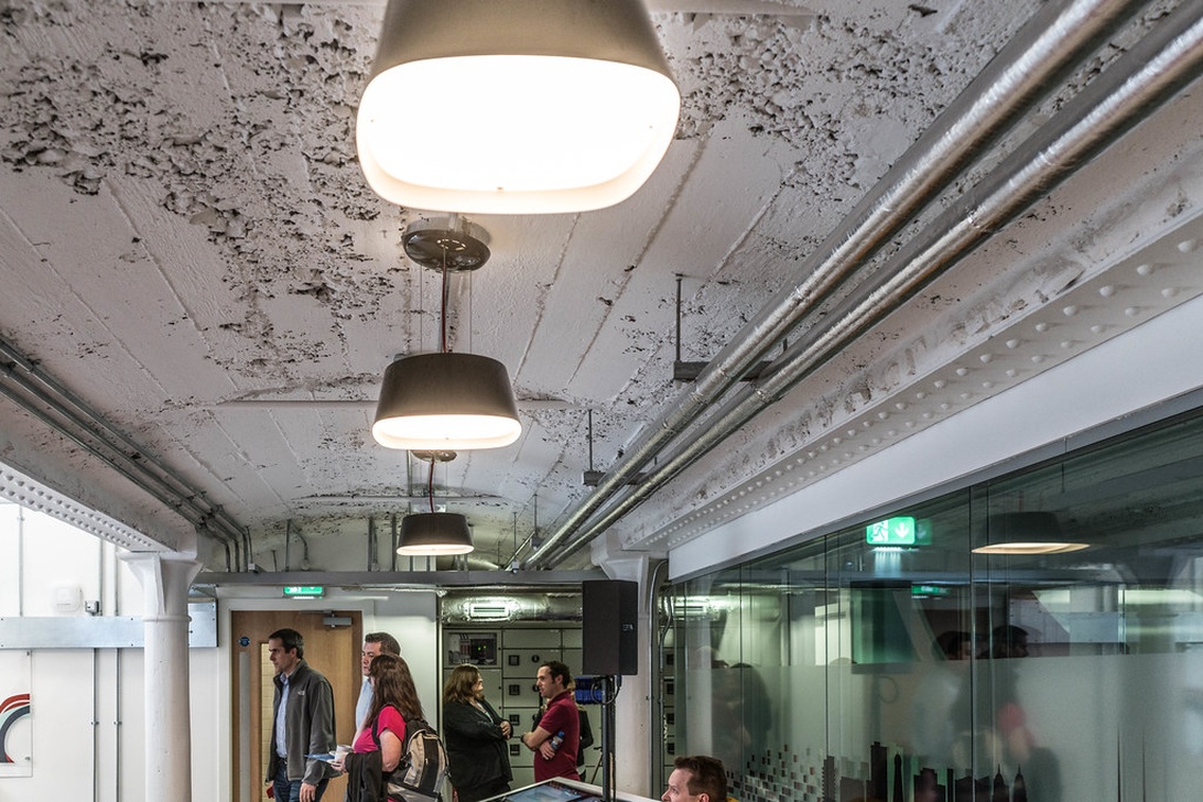 Korridor i industriell stil i en modern kontorsbyggnad med exponerat betongtak och glaspartier.